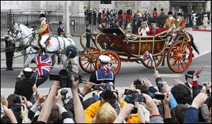 Throngs of people cheer the new Duke and Duchess of Cambridge as they leave Westminster Abbey in a horse-drawn open carriage after their wedding.
