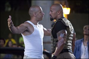 In this film publicity image released by Universal Pictures, Vin Diesel, left, and Dwayne Johnson are shown in a scene from 