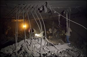 Government officials and members of news media inspect ruins of a house at the site of a NATO missile attack in the Libyan capital of Tripoli. Moammar Gadhafi’s youngest son, Seif al-Arab, and three grandchildren were killed in the attack.