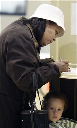 Jacci Croudup of Fremont votes while her daughter Ava Gonzalez, 3, quietly stands by at the Fremont Recreation Center.