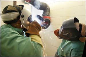 Student MarQuita Malone of Toledo, left, welds under the direction of instructor John Racick at the Owens Community College Welding Center in Perrysburg Township.
