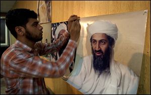 A Pakistani man hangs photos of al-Qaeda leader Osama bin Laden, taken by Pakistani photographer Mazhar Ali Khan, for display at the National Press Club in Islamabad, Pakistan.