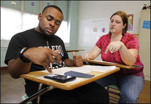 Scott High School’s Denzel Moore, left, uses his calculator to figure a math conversion problem as teacher Melody Basta looks on.