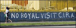 People walk past graffiti in Dublin's city center Tuesday, ahead of the visit by Britain's Queen Elizabeth II. The CIRA refers to the Continuity Irish Republican Army, a republican dissident group.