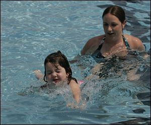 Katie Bertsch, of Toledo, teaches daughter Addison Bertsch, then 4, to swim last summer at Rolf Park Pool in Maumee.