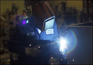 Chad Bitz welds the bottom section of a dust collector for Chrysler's Trenton (Mich.) Engine Plant. About 25 percent of Monroe Environmental Corp.'s work is for auto companies, down from 70 percent.