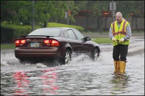 Toledo sewer worker Al Rose works on a flooded portion of the Martin Luther King, Jr., Bridge. The National Weather Service said 1.73 inches of rain fell on the Toledo area Wednesday.