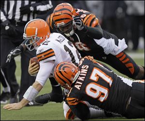 Cleveland Browns quarterback Colt McCoy (12) is sacked by Cincinnati Bengals defensive end Carlos Dunlap (96) and defensive tackle Geno Atkins (97) in a Dec. 19, 2010, game in Cincinnati. 