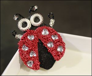 Gourd shells, rhinestones, and microbeads are used to craft a lady bug pin. The pins retail for $10. 