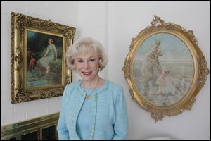 Jill Koehler of Toledo poses with two of Church's paintings, his 1911 