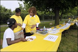 Eric Reynolds, his sister Fionne Wright, center, and Catherine Robinson staff one of the tables set up at the Lucas County Recreation Center in the bid to set a world record for the longest lemonade stand.