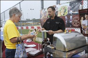 Mary Rumschlag of Maumee and a volunteer at the event, left, gets a plate of chicken from Scott McDole of Granite City Food and Brewery, which donated the food. The event was to help children fight cancer.