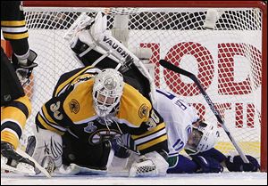 Vancouver Canucks center Ryan Kesler (17) falls over Boston Bruins goalie Tim Thomas (30) in the second period during Game 6 of the NHL hockey Stanley Cup Finals.