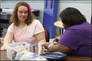 Sarah Schlosser, 14, has her nails done by Ashli Kimmones, one of nine 'life coaches' working at the Self Reliance Center at 2040 West Central Ave. Teens and young adults socialize, play games, learn to do daily chores, and work on other skills.
