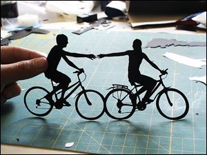 Joe Bagley displays his 'Holding Couple Riding Bikes' paper art.