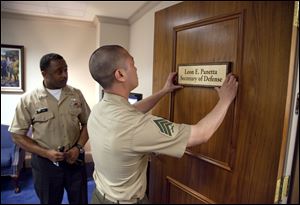 Marine Sgt. John Kang attaches the name plate of incoming Defense Secretary Leon Panetta to his office door at the Pentagon.