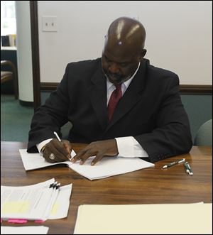 Mayor Mike Bell signs the paperwork for the sale of the Marina District to Dashing Pacific Group, Ltd., in Toledo Saturday, shortly before the Chinese company unveils their plans for the site.