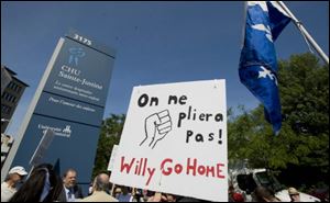 A protester holds up a sign as he awaits the arrival of The Duke and Duchess of Cambridge at Ste-Justine Children's Hospital in Montreal on Saturday.