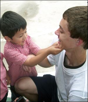 A nursery schooler looks at the braces on Mark Brahler's teeth during the trip by St. John's students to work at the school funded by International Samaritan.