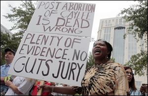 Flora Reece protests outside the Orange County Courthouse with a sign that reads, 