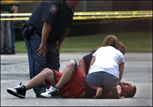 A man who claimed his daughter was inside a house where three bodies were found collapses in the street Thursday in Grand Rapids, Mich. Police say seven people were fatally shot at two locations in the western Michigan city.