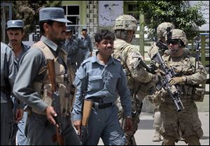 Afghan police men and U.S. soldiers are seen outside the hospital, where the body of Ahmed Wali Karzai, half brother of Afghan President Hamid Karzai, was taken in Kandahar, south of Kabul, Afghanistan, after being fatally shot Tuesday.
