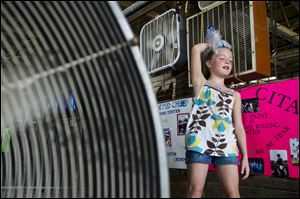 Abigail Gregory, 7, holds an ice bag on her head Monday as she leans up against fans set up in the horse barn at the Bartholomew County 4-H Fair near Columbus, Ind. 