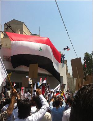 Protesters hang a Syrian flag at the entrance of the U.S. Embassy compound in Damascus. Hundreds of government supporters breached the wall of the compound Monday, smashing windows and painting walls with obscenities before being dispersed by U.S. Marine guards. 