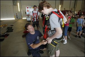 Toledo Fire Department Capt. Bryce Blair, left, connectsa harness to Thomas Petrey.