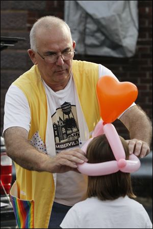 Balloon artist Steve Kurr fits a heart-topped balloon hat to a girl at the Christmas in July celebration. Mr. Kurr's offerings were among the activities for children.