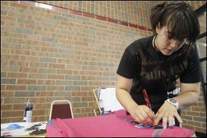 Ms. Mohamed applies paint on a T-shirt using stencils of Japanese characters