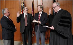 Anthony DeGidio second from left, is sworn in as a member of the Lucas County Board of Elections by Toledo Municipal Court Judge Bill Connelly, right. City councilman George Sarantou, left, witnesses the ceremony as Republican Party chairman and board of elections member Jon Stainbrook, third from left, holds the bible.