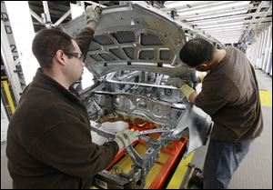 Assembly line workers Dave Zamora, left, and Steven Saleem work on a pre-production Chevrolet Sonic at the General Motors Orion Assembly plant in Orion Township, Mich.
