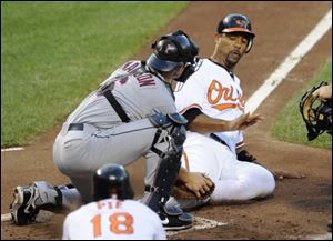 Baltimore Orioles first baseman Derrek Lee, right, is tagged out at home by Cleveland Indians catcher Lou Marson during the fourth inning Saturday.