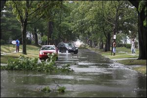 Neighbors along Northwood Ave. near Christie St. come outside to look at the downed branches in on their street after a downpour on July 18, 2011.