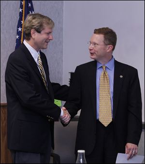 Board of Elections member Jon Stainbrook, left, congratulates Ben Roberts after Mr. Roberts was sworn in as director of the elections board.