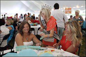 Mrs. Midwest Galaxy Katie Maskey, center, sells raffle tickets to Kim Fenneken, left, and Tiffany Holdgate during the Chicks for Charity mix at the Toledo Botanical Garden. The event raised funds for a boxing club.