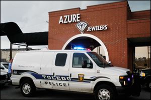 A Toledo police van sits in front of Azure Jewelers in the Executive Shoppers Center after a robbery Friday afternoon.