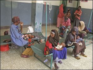 Somali women sit with their children as they are treated in Banadir Hospital in Mogadishu, Somalia. Drought and lack of food force migrations for aid and medical help.