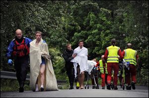 Medics and emergency workers escort youths from a camp site on the island of Utoya, Norway, Saturday.