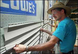 Volunteer Dean Buckenmeyer puts up siding on the house that has been used as transitional housing for men preparing to move out on their own. Single women with children will now find shelter there.