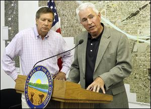 In West Toledo, Gov. John Kasich listens as Jerry Wray, director of the Ohio Department of Transportation, discusses private-sector operation of the Ohio Turnpike.