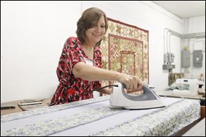 Lisa Sheets of Lambertville irons a quilt made by the Quilts of Compassion sewing group. This year the group will donate quilts to tornado victims in Joplin, Mo. Ms. Sheets, who traveled to Missouri in June, said the experience left a lasting impression.