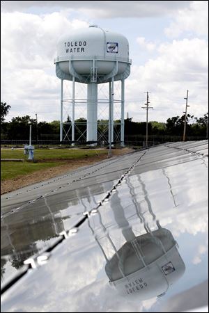 Some of the 12,300 solar panels reflect the water tower at the city's water treatment facility, which will be powered by electricity generated by the new $5.2 million project the city unveiled.