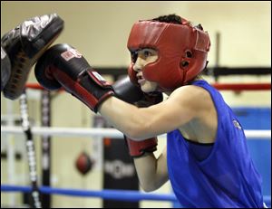 Monica Van Pelt works out at Riverside School, above, while coach Darrie Riley helps her with her chin strap on her headgear, below. Van Pelt is 13-1 in her career and is expected to be ranked No. 1 in her weight class by USA Boxing.