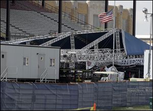 A flag flies at half-staffed near the collapsed stage Indiana State Fair in Indianapolis Monday. Five people were killed Saturday night in the accident. 