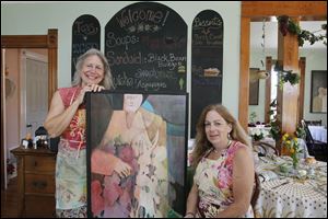 Blissfield artist Peg Stevenson, left, poses with one of her works and Dragonfly Tea Cottage proprietor Jennifer Blakeman.