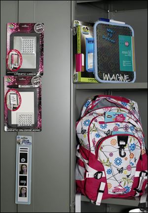 A locker holds supplies that include a floral-print bookbag, magnetic photo strip, and magnetic mirror