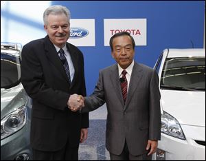 Derrick Kuzak, Ford Motor Company group vice president, Global Product Development, left, and Takeshi Uchiyamada, Toyota Motor Corporation executive vice president, Research & Development shake hands at a news conference in Dearborn.