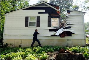Darrell Tarte, a property estimator with Erie Insurance, surveys damage from a tree at a home in Port Republic, Md. after Hurricane Irene Sunday, Aug. 28, 2011. Hurricane Irene left nearly a million people without power in the Mid-Atlantic region Sunday, filling low-lying roads with water and bringing trees down on power lines, streets and rail tracks.
